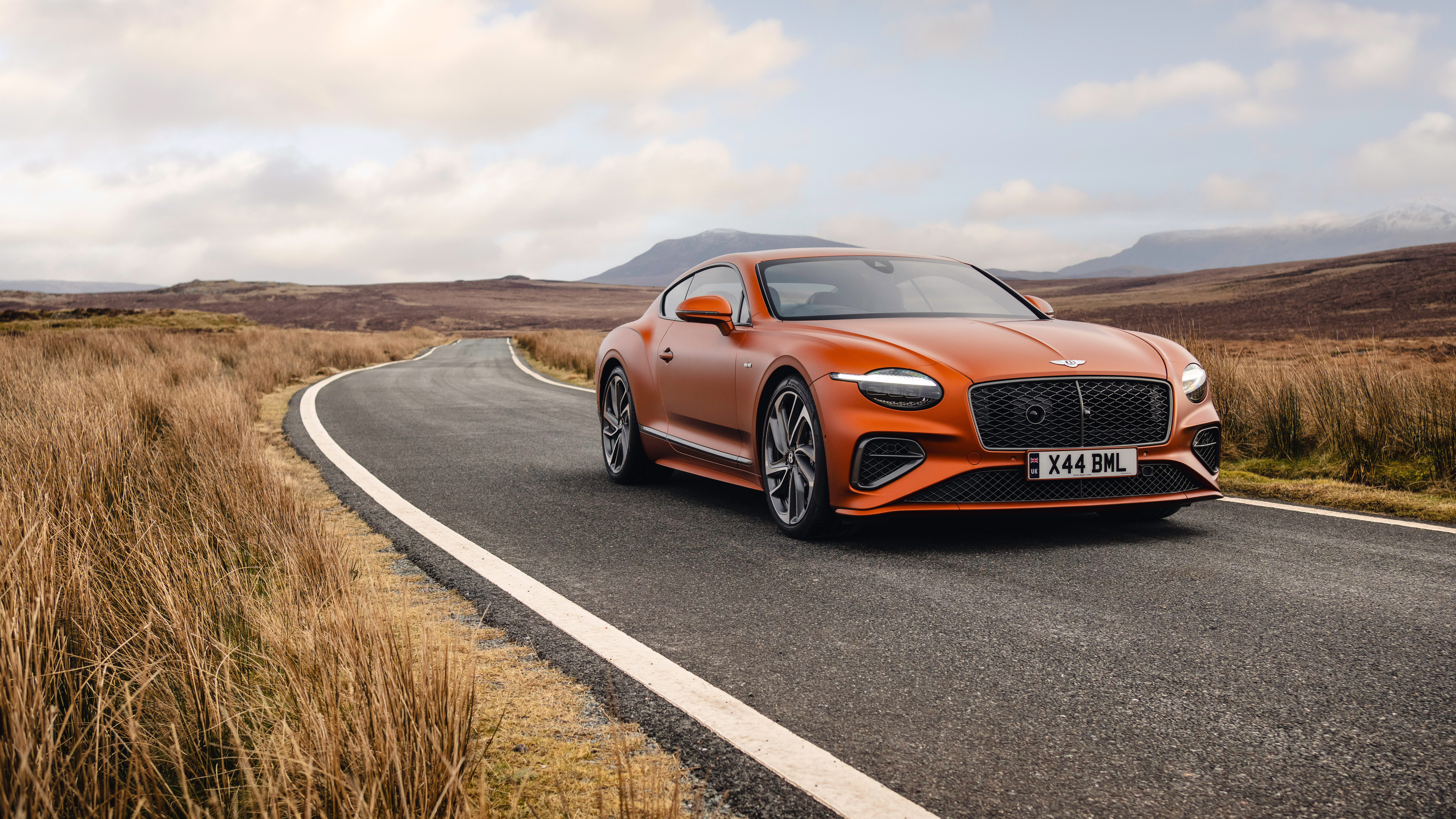 Um deslumbrante Bentley Continental GT Speed de cor laranja vibrante, que exibe o seu design luxuoso e a sua imponente presença.