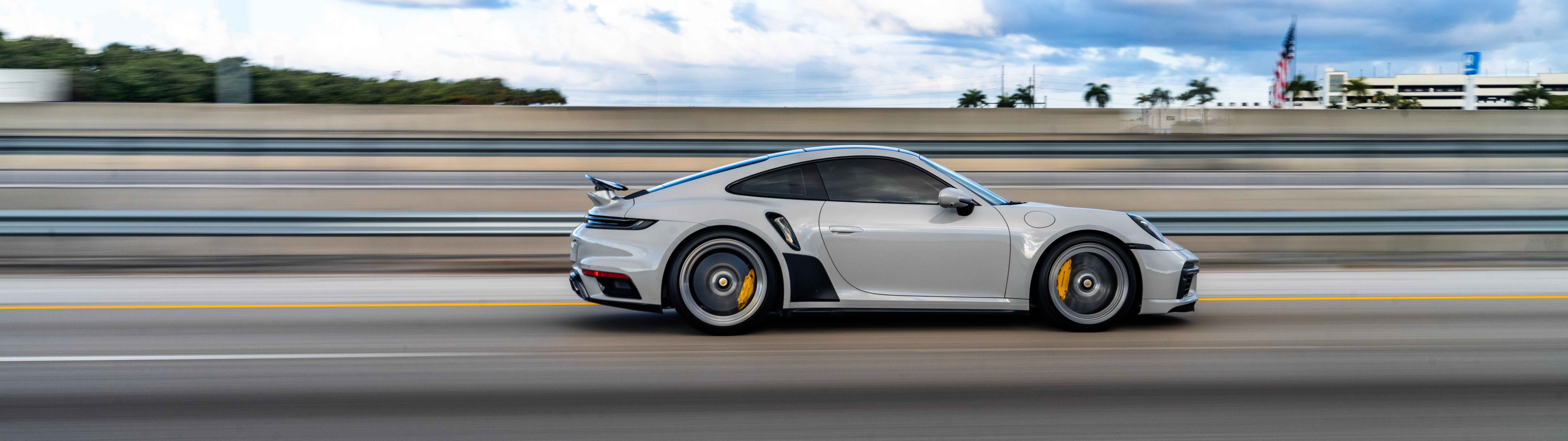 Uma imagem em close de um luxuoso carro esportivo Porsche, destacando o seu design elegante e o acabamento metálico.